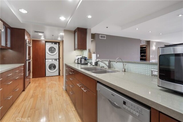 10660 Wilshire Blvd Unit 609, Los Angeles, CA 90024 - kitchen with stainless steel appliances, stacked washing machine and dryer, light wood-type flooring, light countertops, and recessed lighting