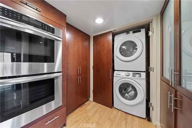 10660 Wilshire Blvd Unit 609, Los Angeles, CA 90024 - laundry room with estacked washer and dryer and light wood-style flooring
