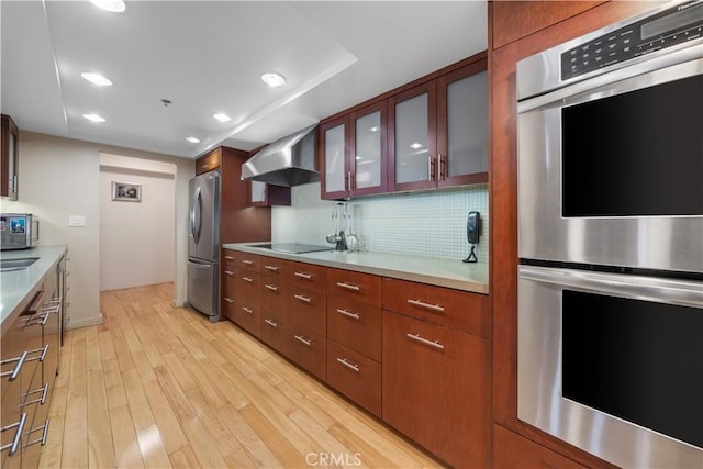 10660 Wilshire Blvd Unit 609, Los Angeles, CA 90024 - kitchen featuring stainless steel appliances, wall chimney range hood, light wood-style floors, tasteful backsplash, and recessed lighting