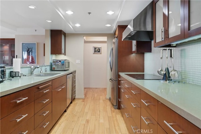10660 Wilshire Blvd Unit 609, Los Angeles, CA 90024 - kitchen with wall chimney range hood, appliances with stainless steel finishes, tasteful backsplash, light countertops, and light wood-type flooring