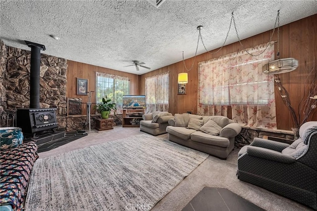 16374 35th Ave Unit 2, Clearlake, CA 95422 - living room featuring carpet floors, a wood stove, wood walls, ceiling fan, and a textured ceiling