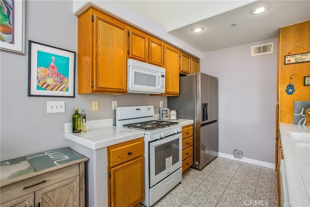 25545 Prospect Ave, Loma Linda, CA 92354 - kitchen with white appliances, tile counters, brown cabinets, and recessed lighting