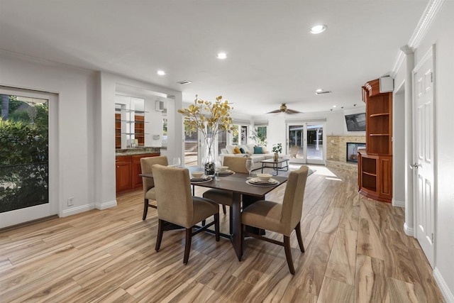15696 Oakstand Rd, Poway, CA 92064 - dining area featuring a fireplace, recessed lighting, light wood-style floors, ceiling fan, and crown molding