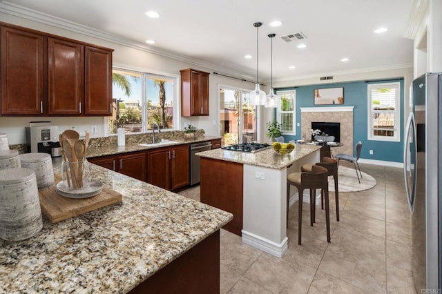 33740 Sattui St, Temecula, CA 92592 - kitchen with stainless steel appliances, a center island, light stone counters, a fireplace, and hanging light fixtures