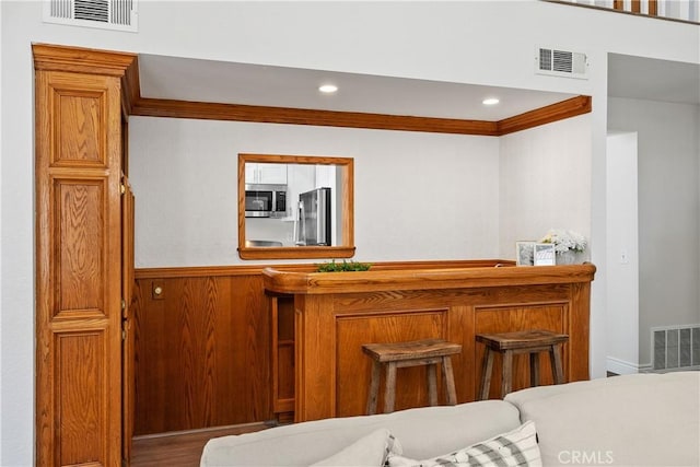 34 Carmel Ct, Laguna Beach, CA 92651 - indoor dry bar featuring appliances with stainless steel finishes, crown molding, recessed lighting, wooden walls, and a wainscoted wall