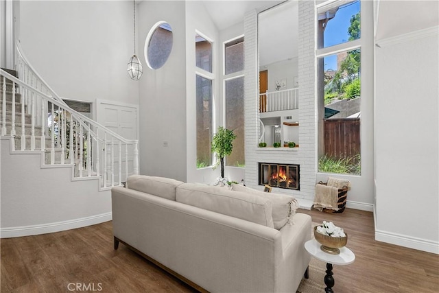 34 Carmel Ct, Laguna Beach, CA 92651 - living area featuring wood finished floors, a towering ceiling, a brick fireplace, and stairway