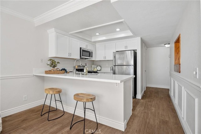 34 Carmel Ct, Laguna Beach, CA 92651 - kitchen with stainless steel appliances, a peninsula, crown molding, a breakfast bar, and white cabinetry