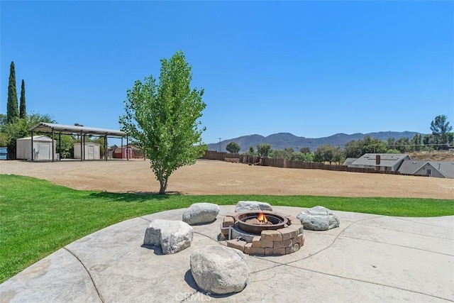 21285 Shoemaker Ln, Wildomar, CA 92595 - view of patio with a storage unit, a fire pit, a detached carport, a mountain view, and dirt driveway