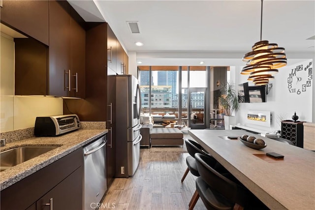 1100 Wilshire Blvd Unit 1707, Los Angeles, CA 90017 - kitchen featuring stainless steel appliances, light wood-style floors, dark brown cabinets, decorative light fixtures, and recessed lighting