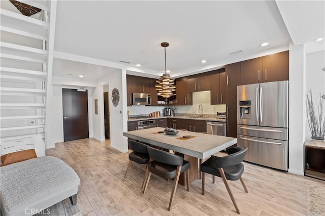 1100 Wilshire Blvd Unit 1707, Los Angeles, CA 90017 - kitchen with stainless steel appliances, dark brown cabinetry, recessed lighting, light countertops, and light wood-type flooring