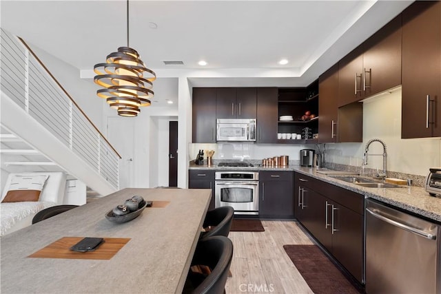 1100 Wilshire Blvd Unit 1707, Los Angeles, CA 90017 - kitchen featuring appliances with stainless steel finishes, open shelves, pendant lighting, light wood finished floors, and light stone counters