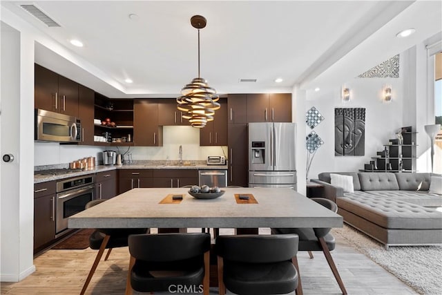 1100 Wilshire Blvd Unit 1707, Los Angeles, CA 90017 - kitchen featuring appliances with stainless steel finishes, dark brown cabinetry, light wood-style flooring, open shelves, and recessed lighting