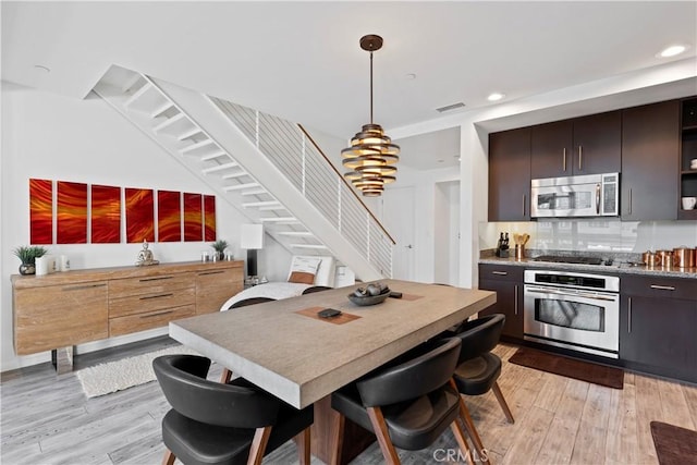 1100 Wilshire Blvd Unit 1707, Los Angeles, CA 90017 - kitchen featuring appliances with stainless steel finishes, light wood finished floors, recessed lighting, hanging light fixtures, and backsplash