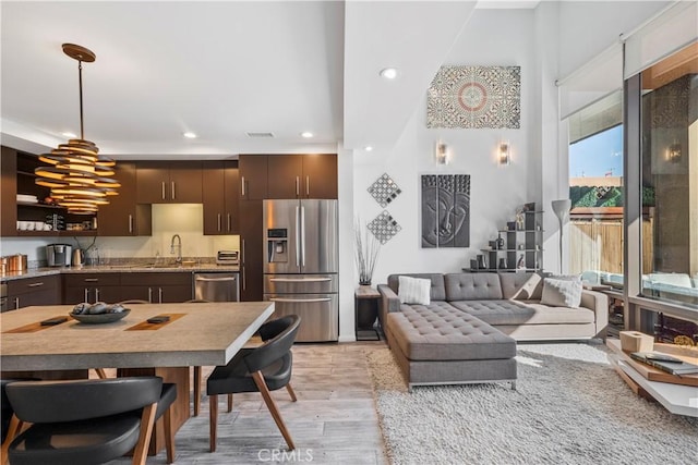 1100 Wilshire Blvd Unit 1707, Los Angeles, CA 90017 - kitchen featuring appliances with stainless steel finishes, light wood-style floors, decorative light fixtures, recessed lighting, and dark brown cabinetry
