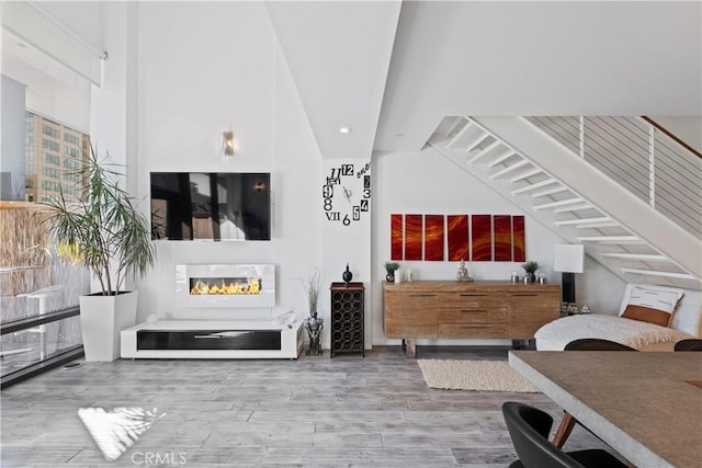 1100 Wilshire Blvd Unit 1707, Los Angeles, CA 90017 - living room featuring a glass covered fireplace, wood finished floors, lofted ceiling, and recessed lighting