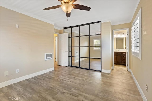 1710 S El Camino Real Unit E204, Encinitas, CA 92024 - unfurnished bedroom with ornamental molding, light wood-type flooring, connected bathroom, a closet, and a ceiling fan