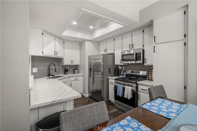 5722 E Stillwater Ave Unit 104, Orange, CA 92869 - kitchen with stainless steel appliances, a tray ceiling, dark wood-type flooring, decorative backsplash, and white cabinetry