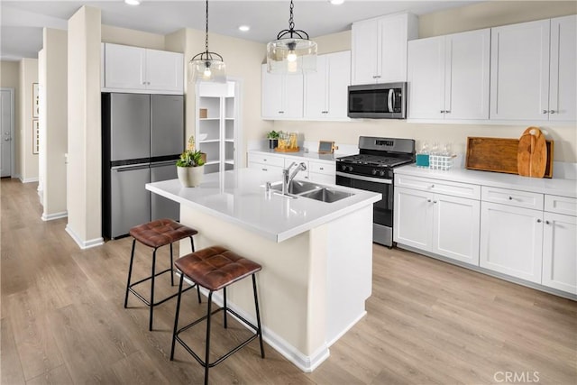 25165 Hunter Ave, Moreno Valley, CA 92551 - kitchen featuring appliances with stainless steel finishes, light wood-style floors, a kitchen breakfast bar, white cabinets, and light countertops