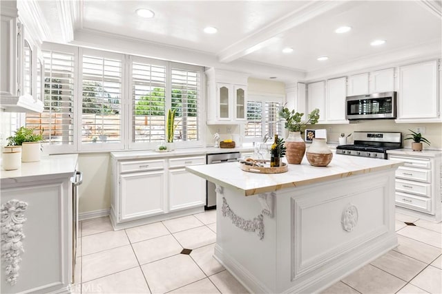 29813 Via Sevilla, Temecula, CA 92591 - kitchen featuring appliances with stainless steel finishes, white cabinets, a center island, light tile patterned floors, and ornamental molding