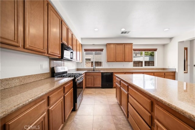 28677 Sunridge Ct, Menifee, CA 92584 - kitchen featuring black appliances, brown cabinetry, light stone countertops, light tile patterned floors, and recessed lighting