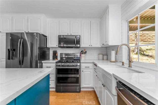 23235 Redbud Ridge Cir, Valencia, CA 91354 - kitchen featuring stainless steel appliances, white cabinets, tasteful backsplash, and light wood-style floors