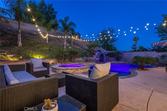 23235 Redbud Ridge Cir, Valencia, CA 91354 - patio at night featuring an in-ground hot tub, a patio, outdoor lounge area, and a fenced backyard