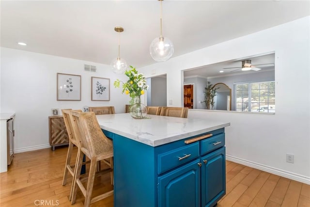 23235 Redbud Ridge Cir, Valencia, CA 91354 - kitchen with blue cabinetry, light wood-style flooring, a breakfast bar area, a center island, and ceiling fan
