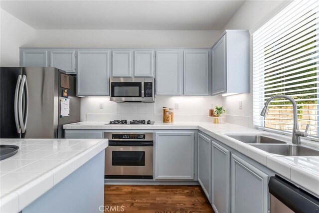 27960 Agapanthus Ln, Valencia, CA 91354 - kitchen featuring appliances with stainless steel finishes, tile counters, and dark wood finished floors