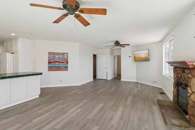 6737 San Miguel Ave, Lemon Grove, CA 91945 - unfurnished living room with a ceiling fan, light wood-style flooring, recessed lighting, and a stone fireplace