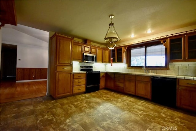 913 Northview Cir, Yreka, CA 96097 - kitchen featuring black appliances, brown cabinetry, a wainscoted wall, glass insert cabinets, and hanging light fixtures