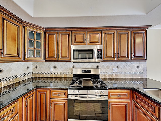2030 Kingsbridge Way, Oxnard, CA 93035 - kitchen featuring appliances with stainless steel finishes, tasteful backsplash, dark stone counters, and glass insert cabinets