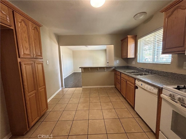 810 E Silva St, Long Beach, CA 90807 - kitchen with white appliances, light tile patterned flooring, brown cabinetry, dark countertops, and a peninsula