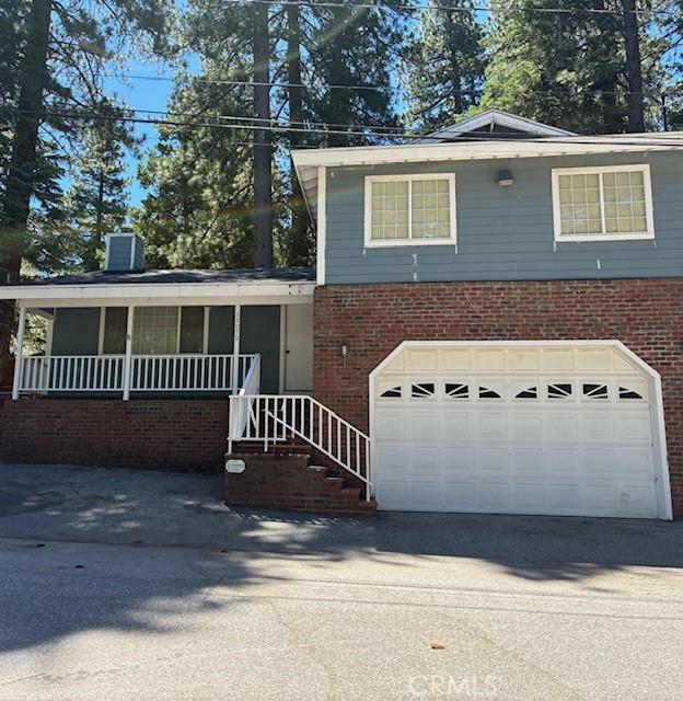 32079 Fern Dr, Running Springs, CA 92382 - view of front facade featuring brick siding, concrete driveway, a chimney, and an attached garage
