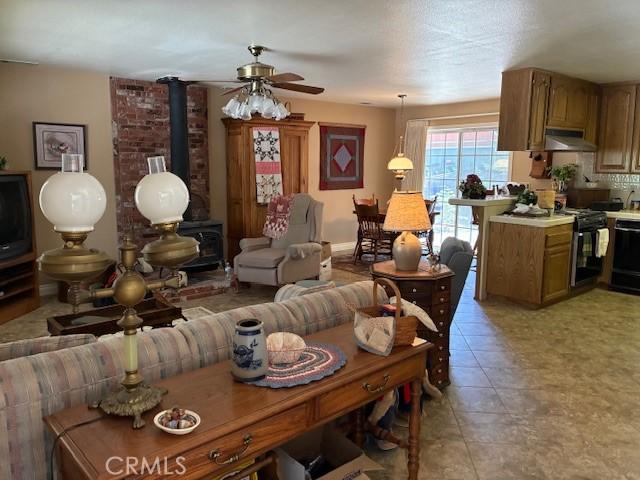 32079 Fern Dr, Running Springs, CA 92382 - living room featuring a wood stove, a ceiling fan, and light tile patterned flooring