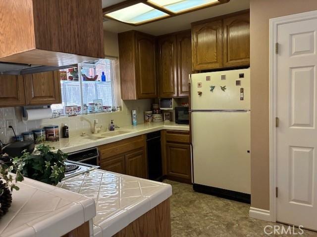 32079 Fern Dr, Running Springs, CA 92382 - kitchen featuring freestanding refrigerator, tile countertops, brown cabinets, and black microwave