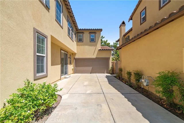 10324 Bold Red Dr, Rancho Cucamonga, CA 91730 - view of side of home with stucco siding, an attached garage, concrete driveway, and a tile roof