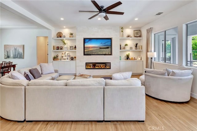 48692 Pear St, Indio, CA 92201 - living area featuring a ceiling fan, light wood-style floors, a large fireplace, built in shelves, and recessed lighting