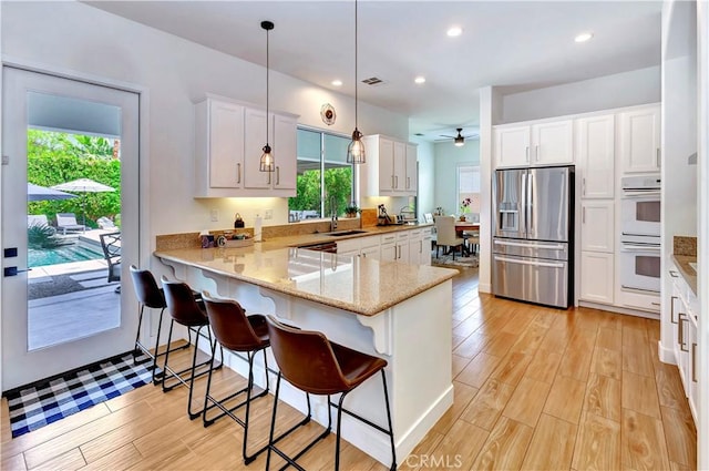 48692 Pear St, Indio, CA 92201 - kitchen featuring stainless steel fridge with ice dispenser, white double oven, a peninsula, healthy amount of natural light, and recessed lighting