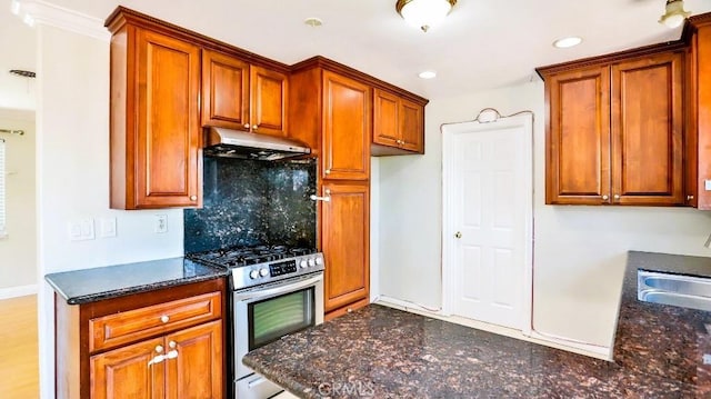 7360 Thunderbird Ln, Stanton, CA 90680 - kitchen with under cabinet range hood, stainless steel range with gas stovetop, decorative backsplash, dark stone counters, and recessed lighting