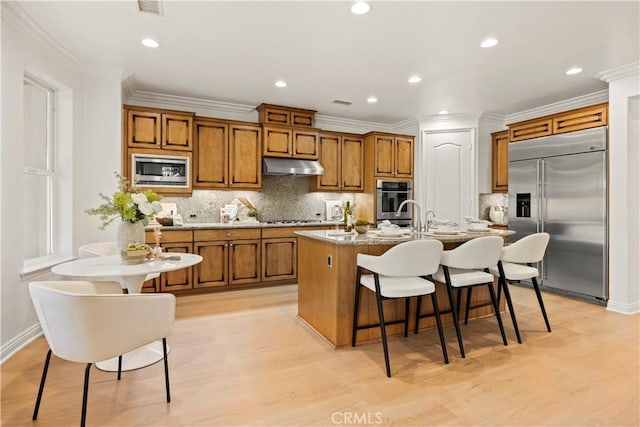 20100 Livorno Ln, Yorba Linda, CA 92886 - kitchen featuring appliances with stainless steel finishes, under cabinet range hood, brown cabinets, a kitchen breakfast bar, and recessed lighting