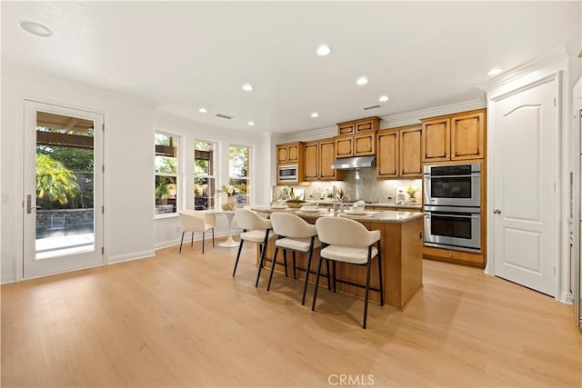 20100 Livorno Ln, Yorba Linda, CA 92886 - kitchen featuring appliances with stainless steel finishes, brown cabinetry, light wood-style flooring, a kitchen bar, and recessed lighting