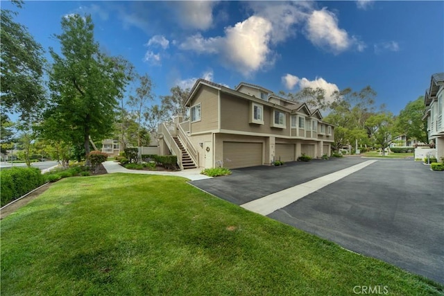 2614 S Quarry Ln Unit D, Walnut, CA 91789 - view of side of property featuring stairs, driveway, a lawn, stucco siding, and a garage
