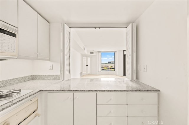 500 W Harbor Dr Unit 808, San Diego, CA 92101 - kitchen with white appliances, light stone countertops, white cabinets, and a peninsula