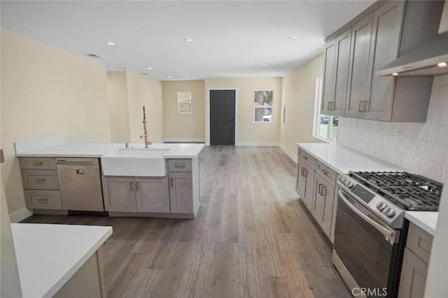 3123 Hyde Park Blvd, Los Angeles, CA 90043 - kitchen featuring stainless steel appliances, wall chimney range hood, light wood finished floors, light countertops, and tasteful backsplash