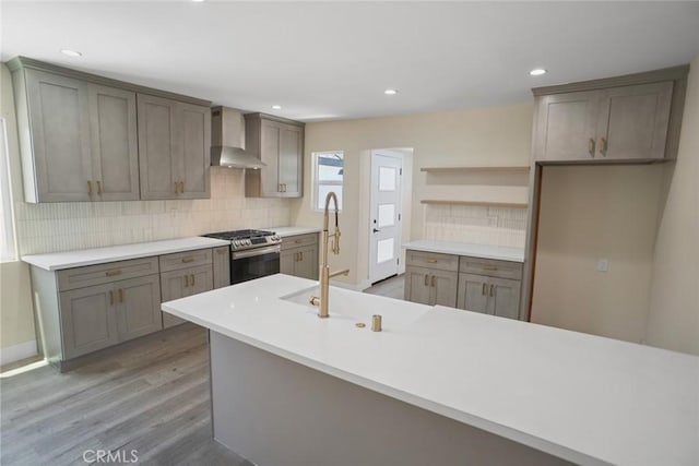 3123 Hyde Park Blvd, Los Angeles, CA 90043 - kitchen with stainless steel gas range, wall chimney exhaust hood, decorative backsplash, light wood-type flooring, and recessed lighting
