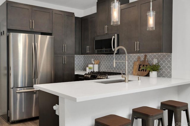 3141 Dega Pl, Carlsbad, CA 92010 - kitchen featuring stainless steel appliances, a peninsula, dark brown cabinets, tasteful backsplash, and light countertops
