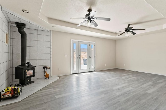 8379 Beaver Ave, Phelan, CA 92371 - unfurnished living room featuring a wood stove, a tray ceiling, wood finished floors, and a textured ceiling