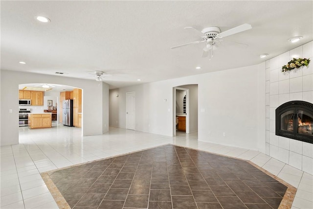 8379 Beaver Ave, Phelan, CA 92371 - unfurnished living room with ceiling fan, light tile patterned floors, recessed lighting, a tile fireplace, and arched walkways