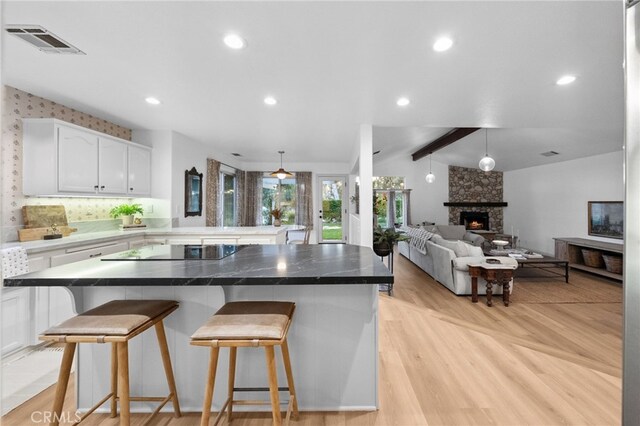 42333 Casa Verde, Temecula, CA 92592 - kitchen with black electric cooktop, white cabinets, a breakfast bar, open floor plan, and a peninsula