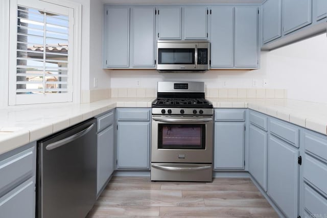 28328 Via Bandita, Menifee, CA 92585 - kitchen with appliances with stainless steel finishes, light wood finished floors, and tile counters